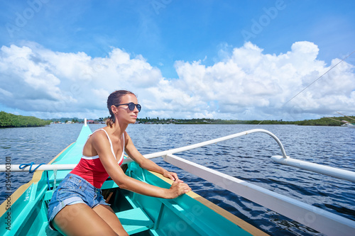 Happy vacation in Philippines. Pretty young woman sailing the sea on traditional boat.