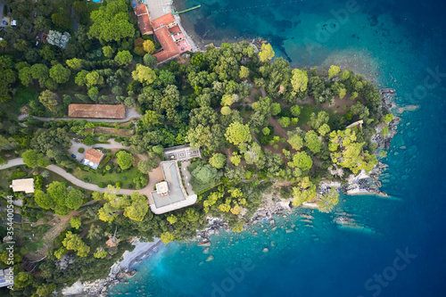 A view above on seashore with green trees and houses with villas. Huge stones in a bottom of Ligurian Sea, Italy