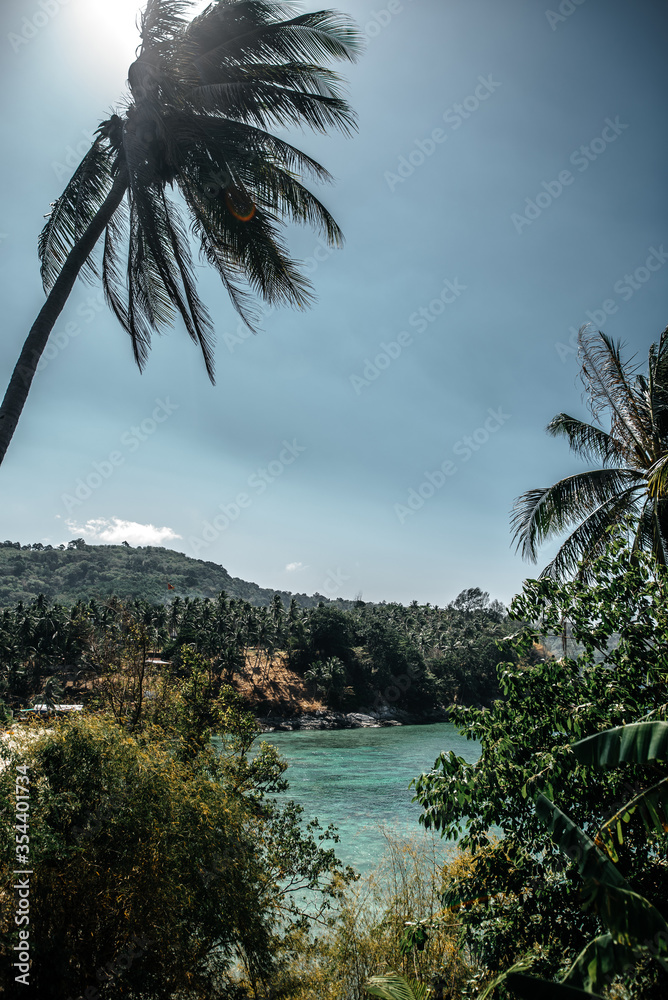 Thailand, 2020: turquoise bay surrounded by jungle trees with bright afternoon light, photo with soft warm light