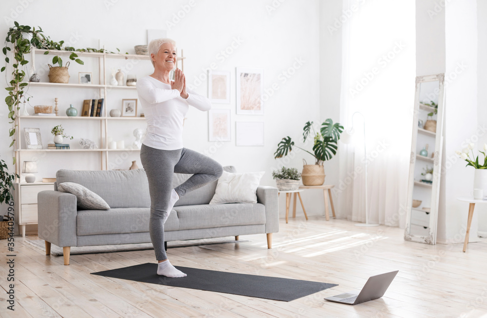 Sporty Senior Woman Practicing Yoga With Online Tutorials At Home - obrazy, fototapety, plakaty 