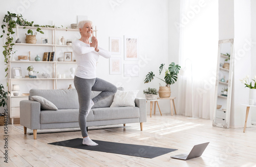 Sporty Senior Woman Practicing Yoga With Online Tutorials At Home