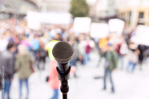 Public demonstration or political protest. Microphone in focus against unrecognizable crowd of people. © wellphoto