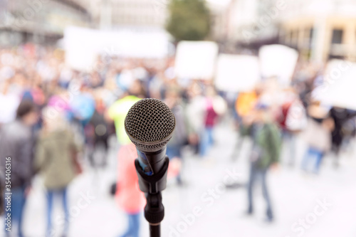 Public demonstration or political protest. Microphone in focus against unrecognizable crowd of people.