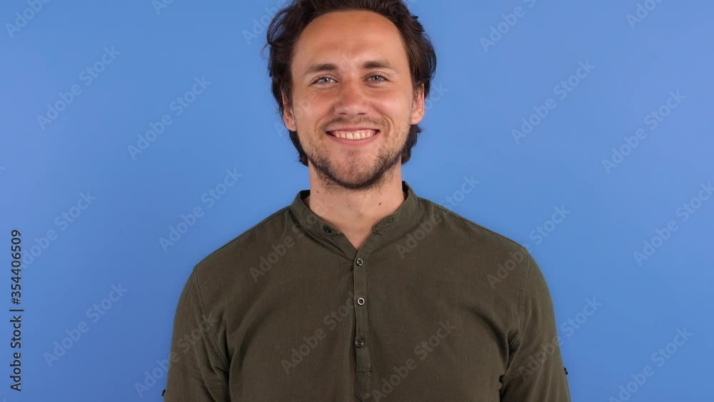 Bearded male in khaki colored shirt. He is smiling and showing ok sign while posing against blue studio background. Sincere emotions. Close up Bearded male in khaki colored shirt. He is smiling and showing ok sign while posing against blue studio background. Sincere emotions. Close up