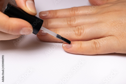 A woman covers her nails with a rubber base for gel polish. Manicure at home.
