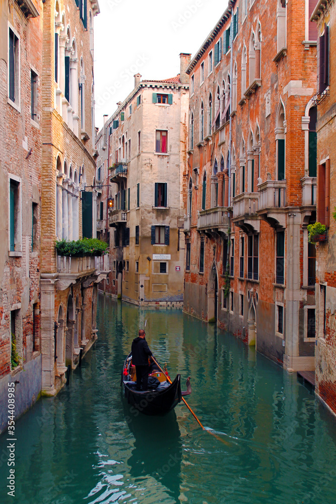 Gondola ride on one of Venice's canals, surrounding by pink buildings characteristic of the city. 