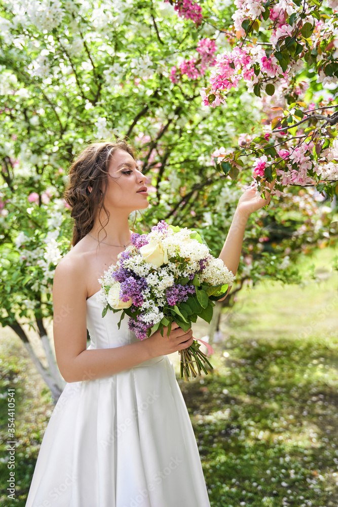 Girl with a bouquet stands at a flowering rose tree, wedding walk Girl with a bouquet stands at a flowering rose tree, wedding walk