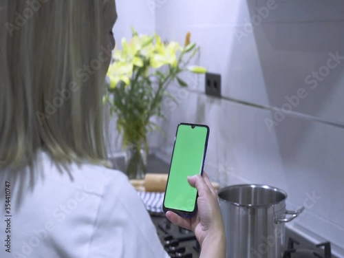 Girl using the phone Green screen in the kitchen, Hands holding the CHROME KEY business smartphone Fingers of the modern smartphone screen touching massage scrolling functions