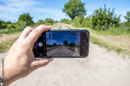 ahand holds a smartphone in his hand and photographs a landscape