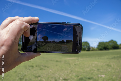 ahand holds a smartphone in his hand and photographs a landscape photo