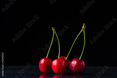 Red cherries on a black background. Two paired sweet cherries. Ripe juicy cherries. only cherries on a black background