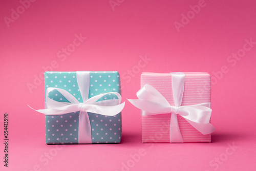 Pink and blue gift boxes with white bows over rose background