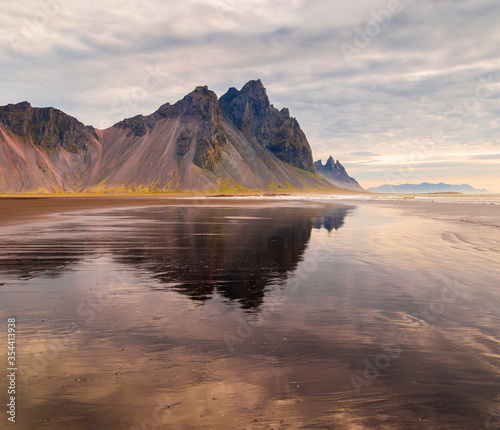 Fantastic view of Mount Vestrahorn (Batman) at low tide at sunrise. Incredible summer morning on the Stokksnes headland. Southeastern Iceland, Europe. Visit Iceland. Beauty world.