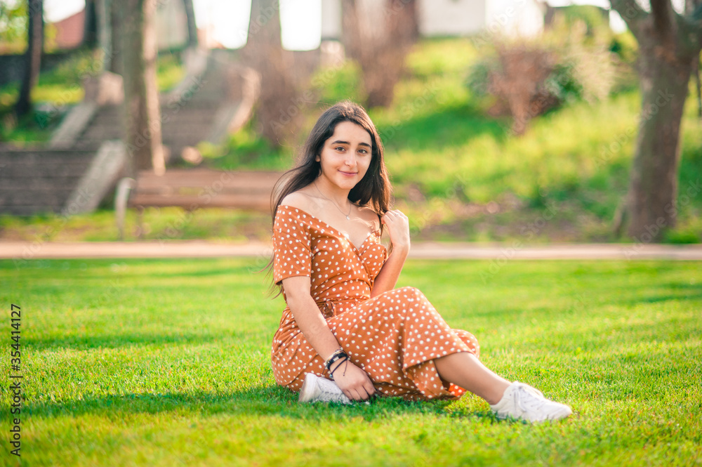 beautiful caucasian girl sitting on the grass in the park. She is looking at the camera. great copy space. beautiful caucasian girl sitting on the grass in the park. She is looking at the camera. great copy space.
