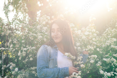 Spring time. beautiful caucasian girl in a bush full of flowers. Lens flare