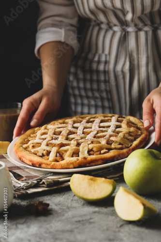 Housewife hold tasty apple pie on gray table. Homemade food photo