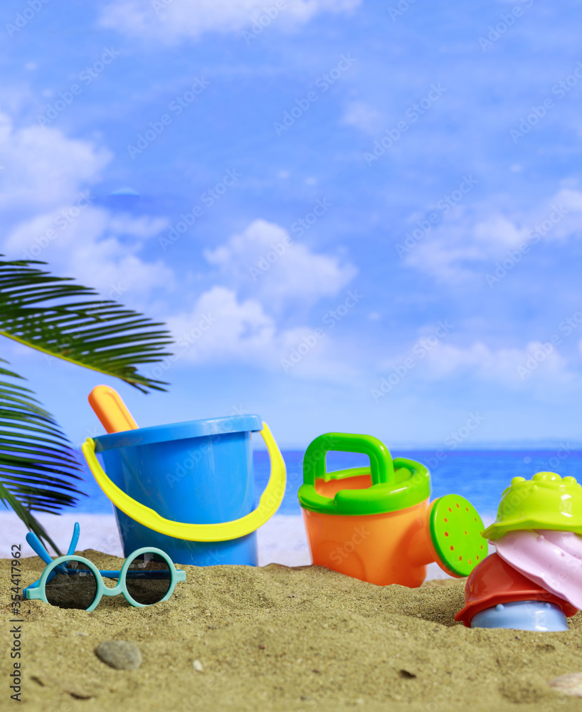 Summer vacations. Plastic toys for kids activities on a sandy beach. Blur sea background Summer vacations. Plastic toys for kids activities on a sandy beach. Blur sea background