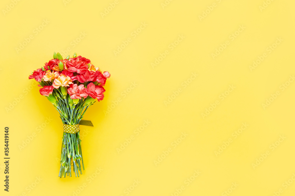Red carnation flowers bouquet on yellow background. Mother's day, Valentines Day, Birthday celebration concept. Copy space, top view