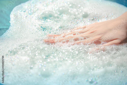 hand in foam, airy soapy foam on the water, take a bath with foam, wash clothes