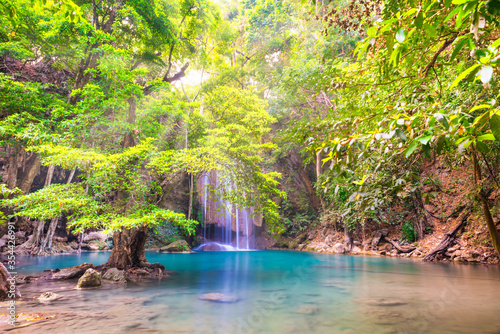 Fototapeta Naklejka Na Ścianę i Meble -  Beautiful waterfall in tropical jungle forest with big green tree and emerald lake on foreground. Nature landscape of Erawan National park, Kanchanaburi, Thailand