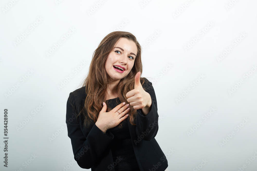 Young Attractive Woman Brunette In In A Black T-Shirt, Sweater On White Background, Happy Female Smiling Raised, Hands And Turned Up Her Thumb Finger. Everything Is Fine, Happiness, Success Of People Young Attractive Woman Brunette In In A Black T-Shirt, Sweater On White Background, Happy Female Smiling Raised, Hands And Turned Up Her Thumb Finger. Everything Is Fine, Happiness, Success Of People