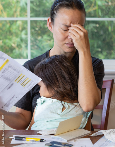 Stressed mother with her child in her lap stressing out about paying utility bills