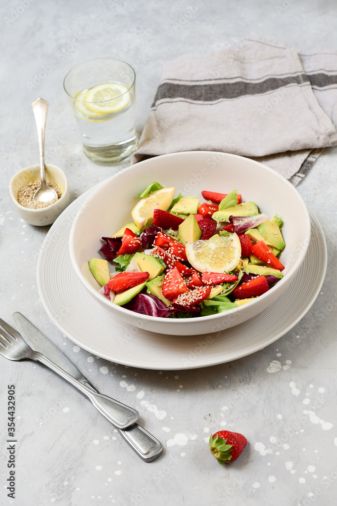 avocado salad with sesame and strawberries on a white plate. fitness keto food recipe. healthy lunch avocado salad with sesame and strawberries on a white plate. fitness keto food recipe. healthy lunch