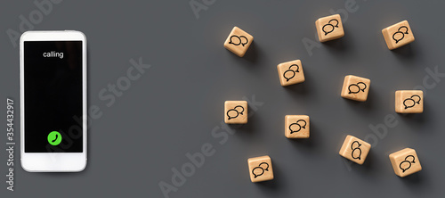 many cubes with speech bubble icons and smartphone on wooden background