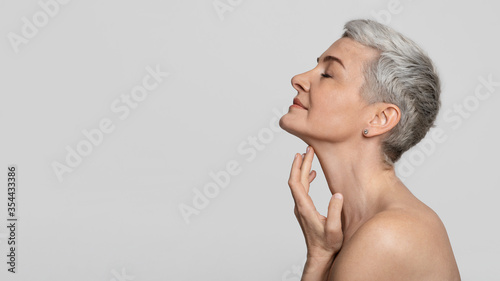 Anti-Age Treatment. Beautiful middle-aged woman touching soft skin on her neck