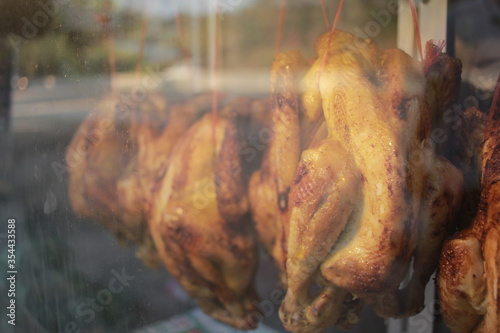 a roast chicken are hang in a glass display