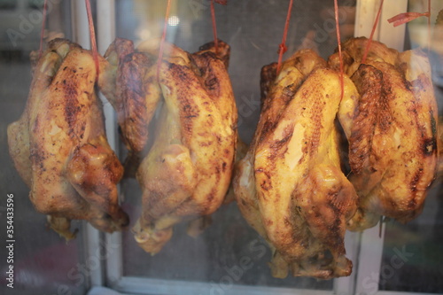 a roast chicken are hang in a glass display