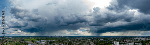 Panoramic view dramatic sky over city. Far village sight under cloudy sky. Aerial Flying over town, far industrial sight beyond