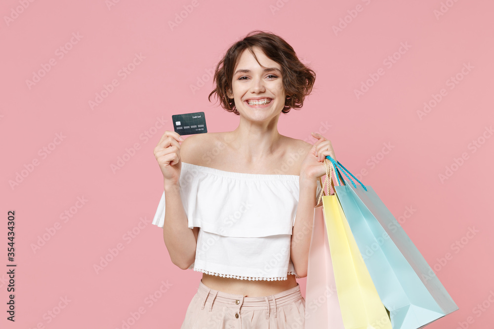 Smiling young woman girl in summer clothes isolated on pastel pink background studio portrait. Shopping discount sale concept. Mock up copy space. Hold package bag with purchases, credit bank card. Smiling young woman girl in summer clothes isolated on pastel pink background studio portrait. Shopping discount sale concept. Mock up copy space. Hold package bag with purchases, credit bank card.