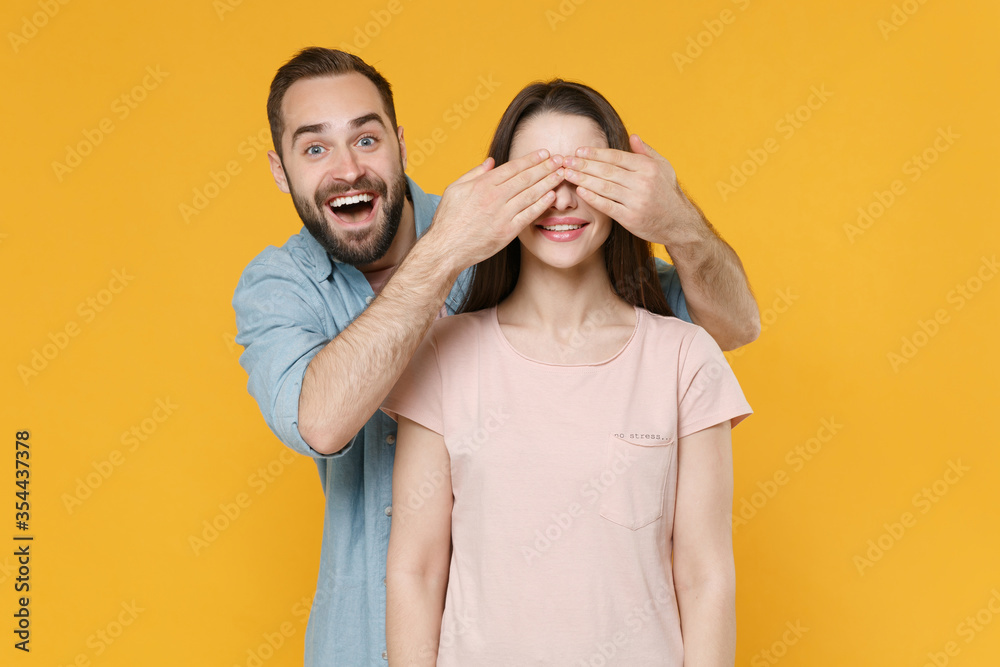 Excited young couple two friends guy girl in pastel blue casual clothes posing isolated on yellow background studio portrait. People lifestyle concept. Mock up copy space. Covering eyes with hands. Excited young couple two friends guy girl in pastel blue casual clothes posing isolated on yellow background studio portrait. People lifestyle concept. Mock up copy space. Covering eyes with hands.