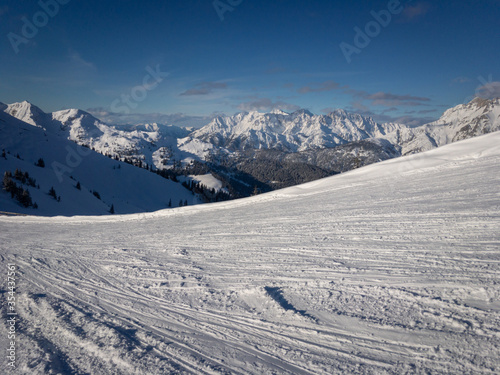 Scenic view of Lofer Mountains with ski slope in the foreground against blue sky.