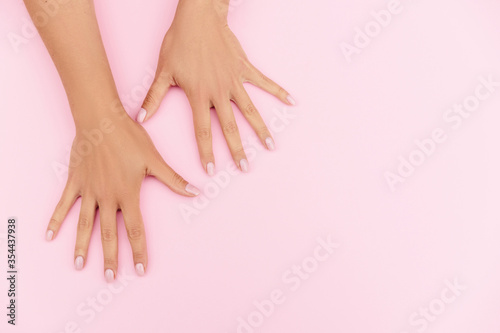 Tender hands with perfect blue and pink manicure on trendy pastel pink background. Place for text.