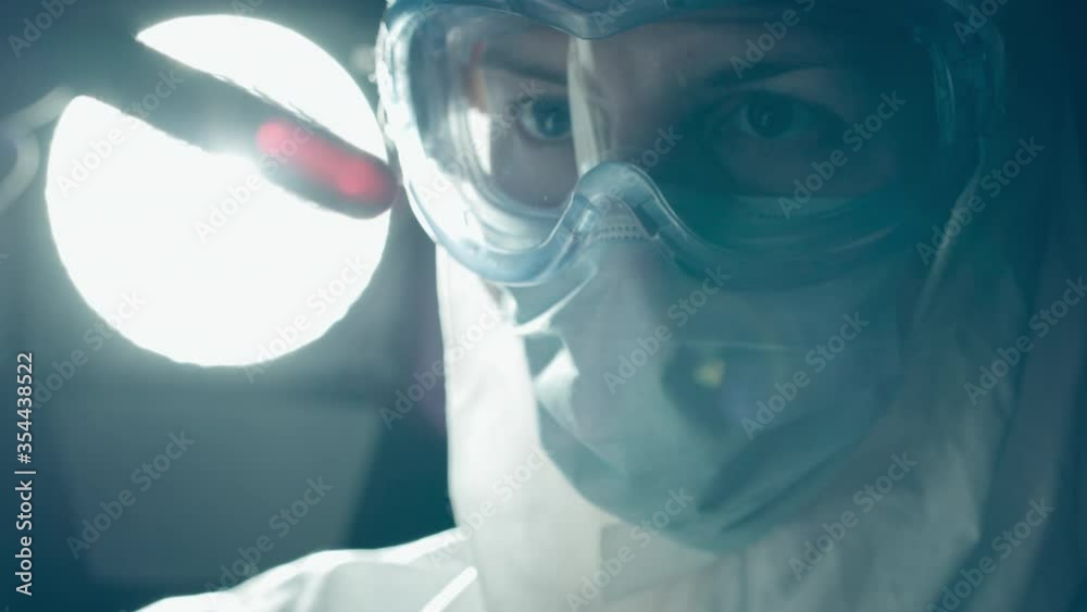 Lab expert in protective gear looking at blood sample tube, infection hazard Lab expert in protective gear looking at blood sample tube, infection hazard