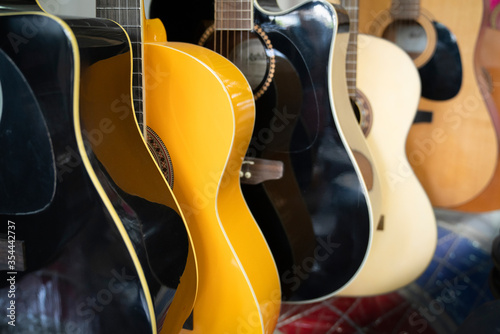 Guitars of different colors are waiting in the shop in a row for sale.