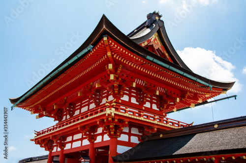 Bright  red religious pagoda with gold trim in Tokyo  Japan against a blue sky with puffy clouds.