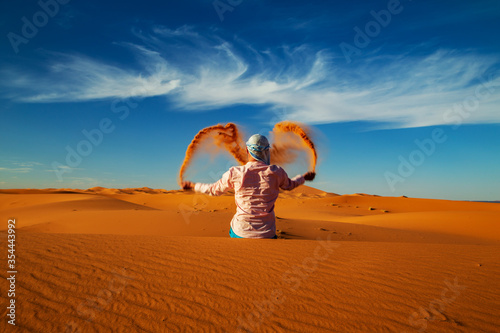 Single Man throws sand in the Sahara desert at sunset. photo