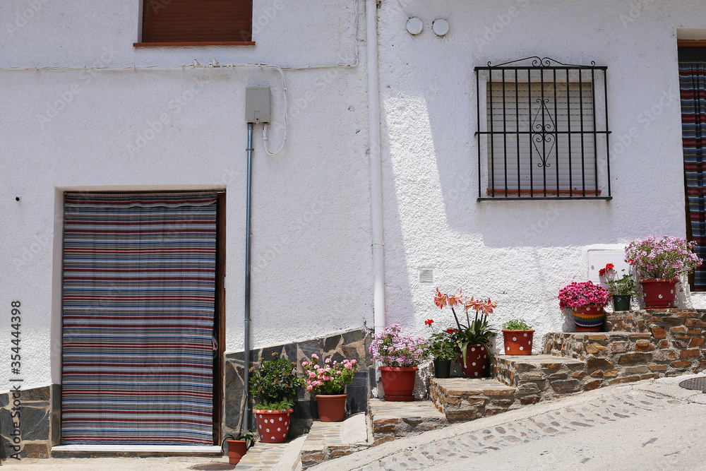 Trevelez village in the Alpujarras mountains, province of Granada, Andalusia, Spain - May 29, 2019: - narrow cobblestone street with whitewashed houses and flower pots.