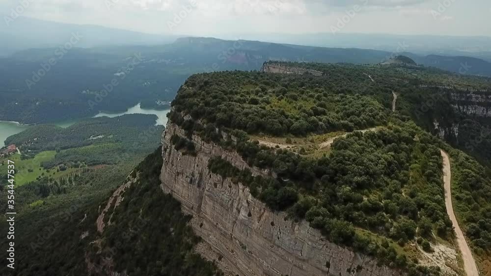 Aerial tilt up shot of rocky mountain near river against cloudy sky, drone flying over natural green landscape on sunny day - Tavertet, Spain Aerial tilt up shot of rocky mountain near river against cloudy sky, drone flying over natural green landscape on sunny day - Tavertet, Spain