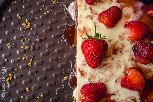 Half delicious cheese cake with small red strawberries