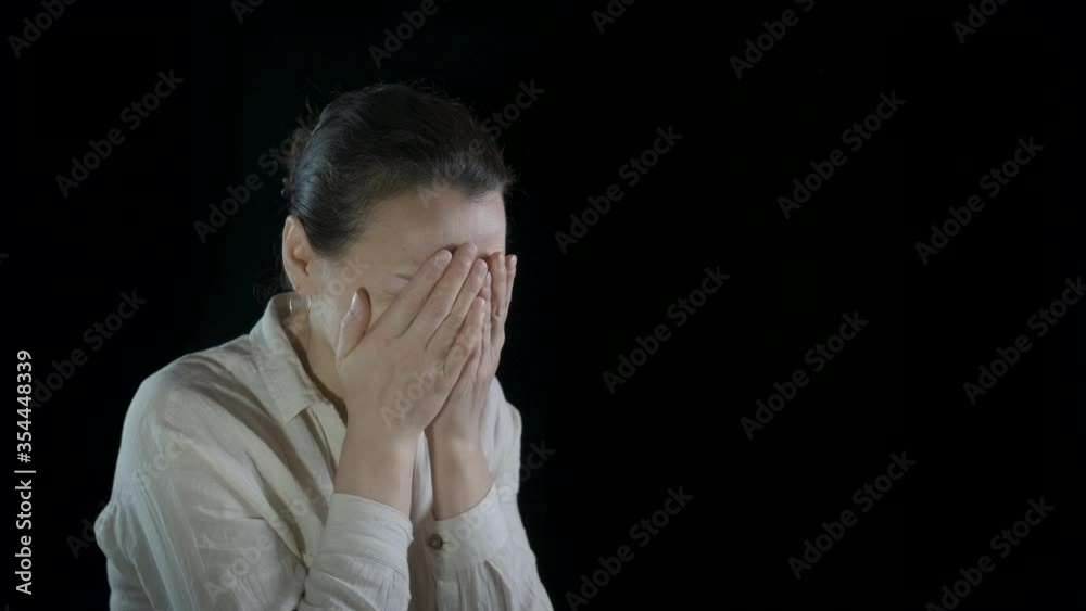 Portrait of a desperate woman. The woman closes her eyes with her hands in despair.