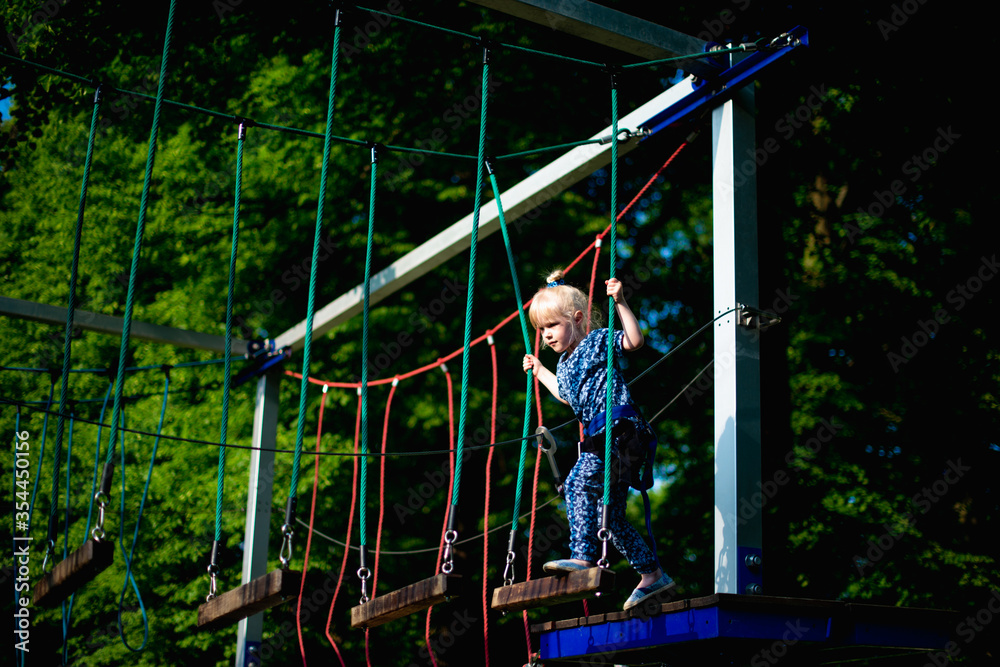 Girl kid enjoying activity in a climbing adventure park on a summer day. Childhood, lifestyle. 