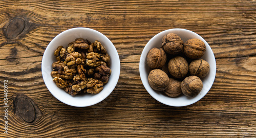 Whole and sheled walnut in a small plates on a vintage wooden table as a background. Walnuts is a healthy vegetarian protein nutritious food. Natural nuts snacks.