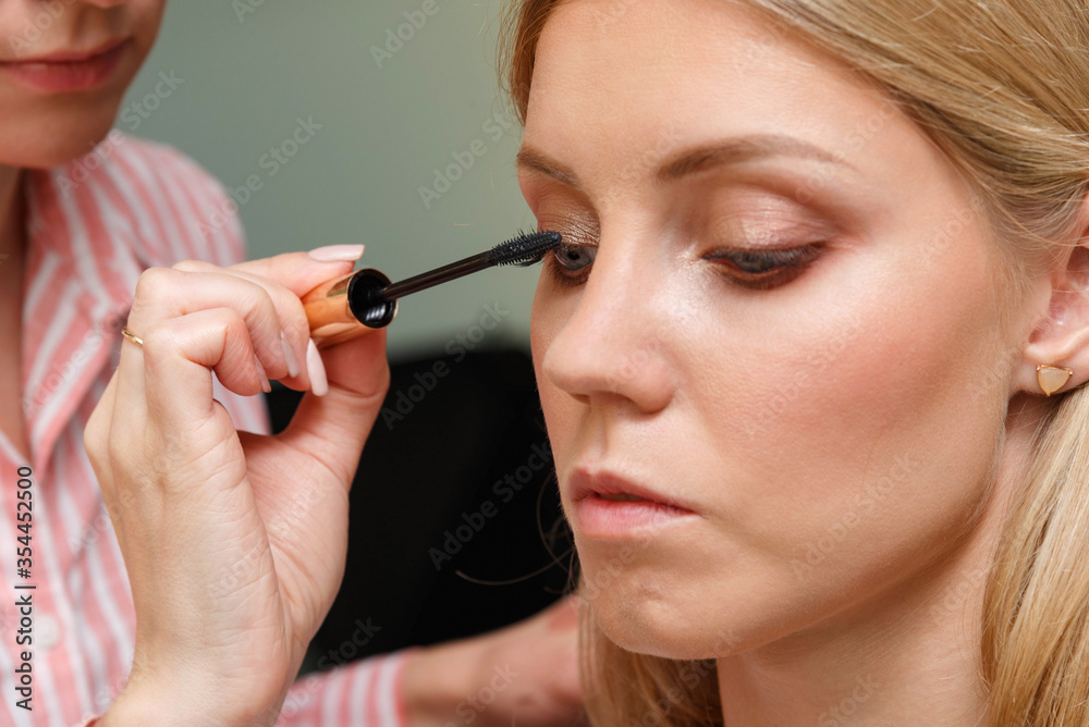 Makeup artist creates voluminous eyelashes of the model.