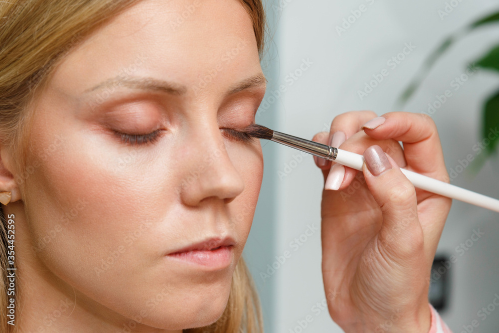 The process of creating makeup. Makeup artist working with a brush on the face of the model. The process of creating makeup. Makeup artist working with a brush on the face of the model.