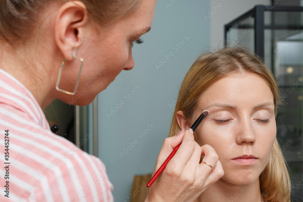 The process of creating makeup. Makeup artist working with a brush on the face of the model. The process of creating makeup. Makeup artist working with a brush on the face of the model.