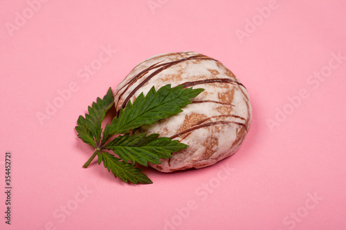 sweet tasty round cookie with marijuana leaf close-up on a pink background. canabis pastries, sweets